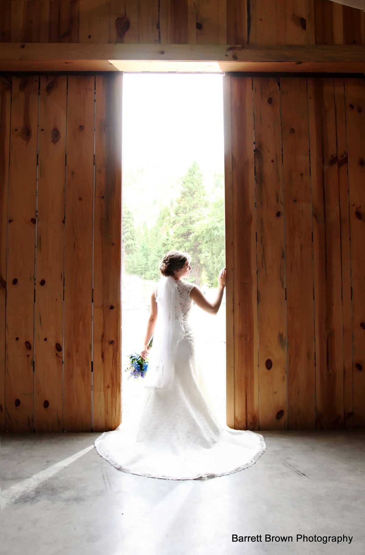 Bride holding her bouquet and touching one of the ceder plank bar doors